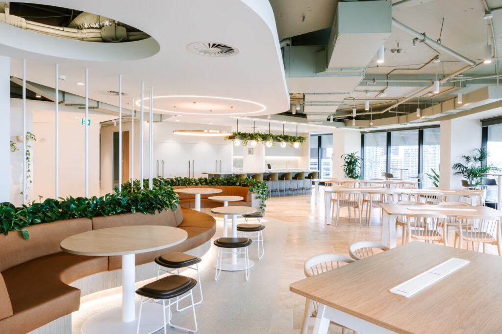 Bright open-plan breakout café and collaboration area at Bentleys Queensland with curved booth seating, integrated greenery, and city views