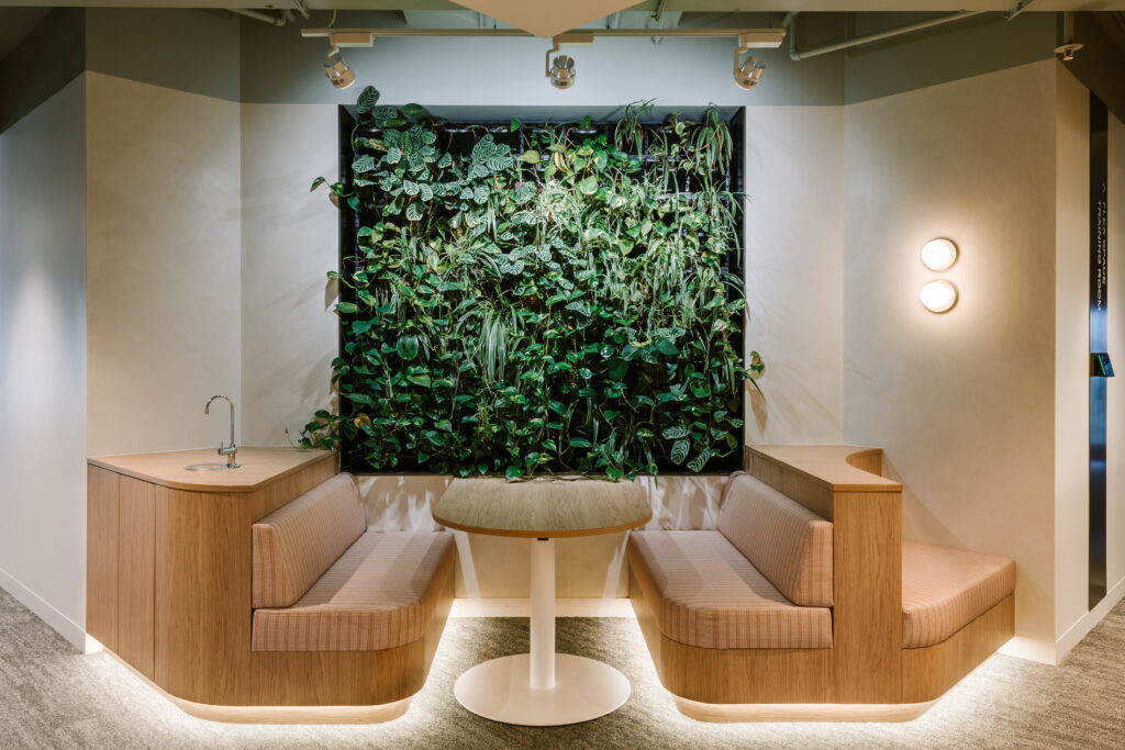 Cozy seating nook with lush living green wall, curved timber booths, and integrated sink at Bentleys Queensland office