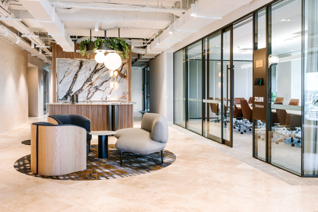 Modern reception lounge at Bentleys Queensland featuring sculptural armchairs, marble feature wall, and glass boardrooms