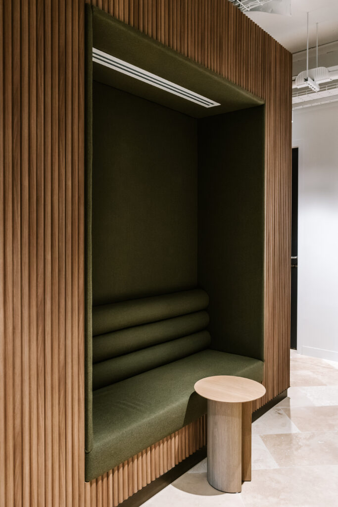 Private acoustic timber booth with deep green upholstered seating and side table at Bentleys Queensland office
