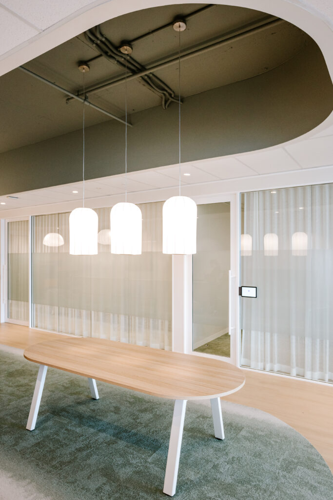Modern meeting room with wooden table and white pendant lights at Children’s Hospital Foundation