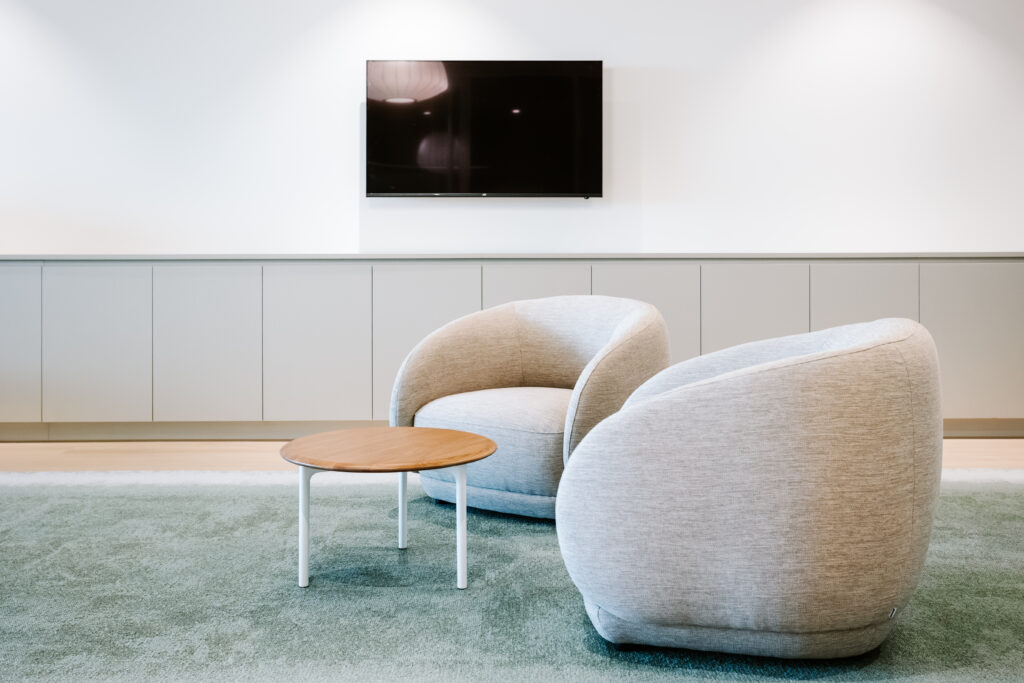 Cozy lounge seating area with curved armchairs and TV in the Children’s Hospital Foundation office