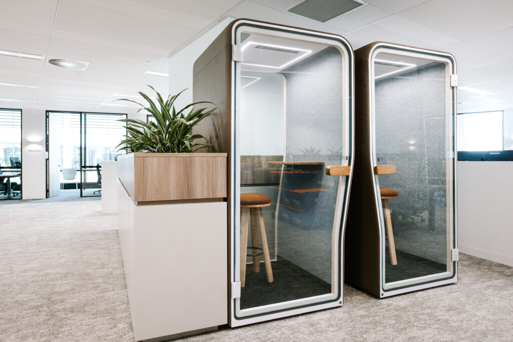Private acoustic phone booths and focus pods with glass doors in the Dentons Brisbane office, accompanied by integrated planter boxes.
